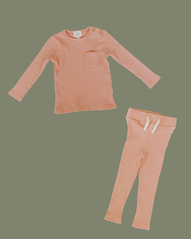 Flat lay image of organic cotton rib two piece set in strawberries and cream color. Set includes a long sleeve top with Magnetic Buttons at the neck in sizes through 12-18 months as well as leggings with a faux drawstring.