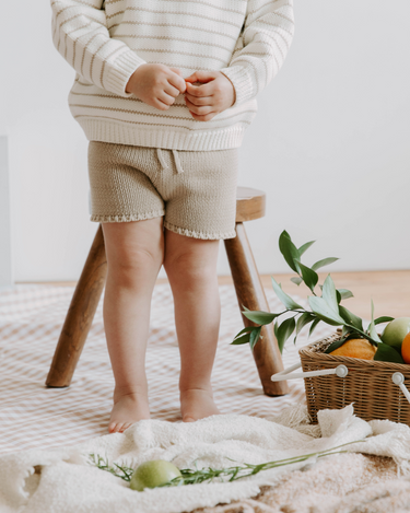Picture of little girl wearing organic cotton knit shorts in Sandcastle color with faux drawstrings. 