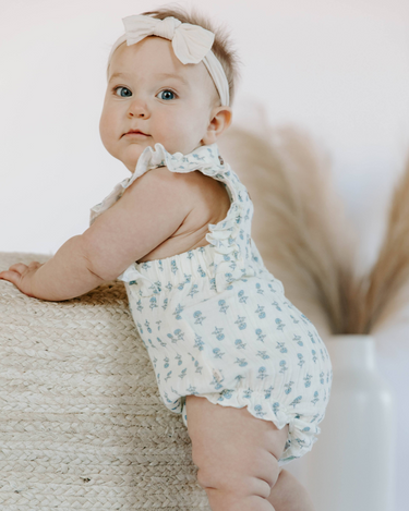 Baby wearing cotton muslin flutter sleeve bubble romper in cheerful floral 
