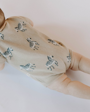 Baby wearing zebra print knit playsuit in mushroom