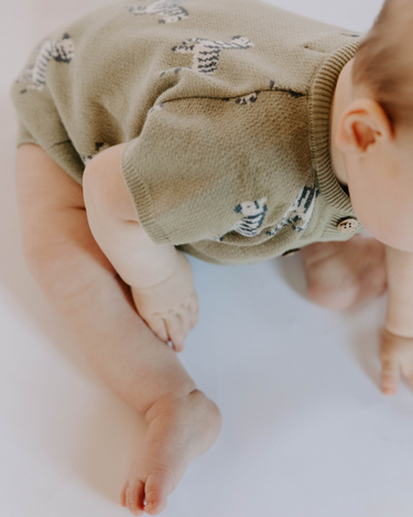 Baby wearing zebra print knit playsuit in sage
