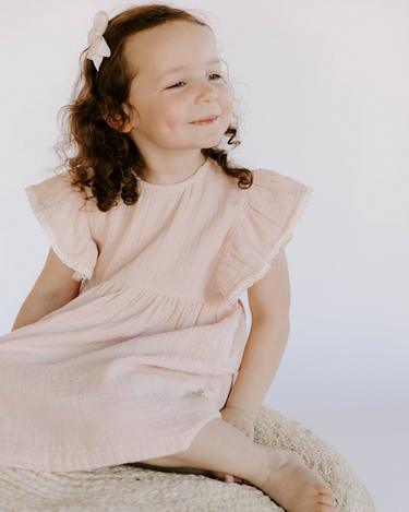 Little girl wearing cotton muslin flutter sleeve dress in orchid pink