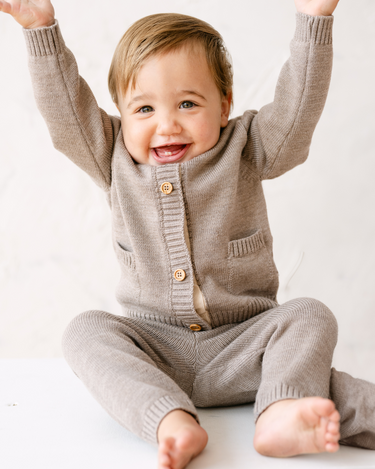 Image shows baby boy wearing merino wool baby gift set in heather brown.