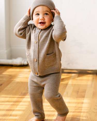 Image shows baby boy wearing merino wool baby gift set in heather brown.