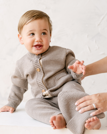 Image shows baby boy wearing merino wool baby gift set in heather brown.