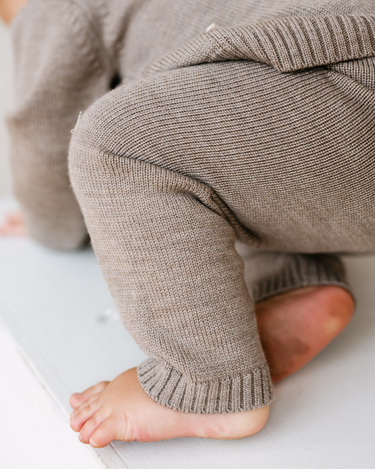 Image shows baby boy wearing merino wool baby gift set in heather brown.