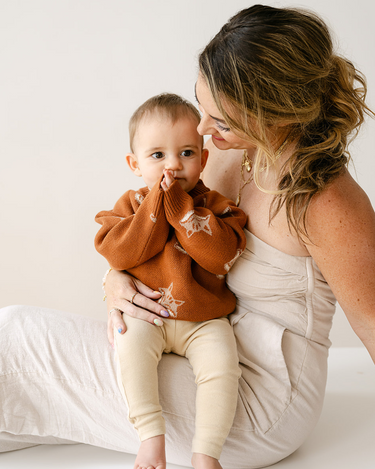 Image shows baby boy wearing organic cotton knit sweater with fox jacquard pattern in mocha.