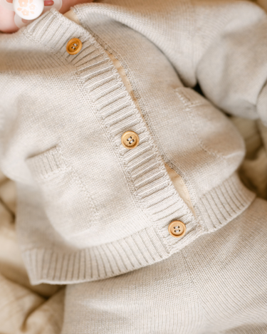 Image shows baby girl wearing merino wool baby cardigan in light heather gray.