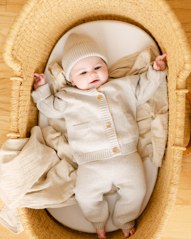 Image shows baby girl wearing merino wool baby cardigan in light heather gray.