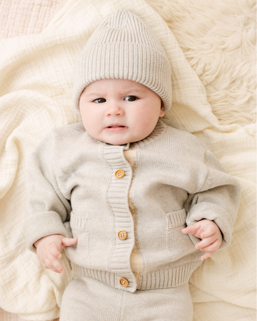 image shows baby girl wearing merino wool baby cardigan in light heather gray