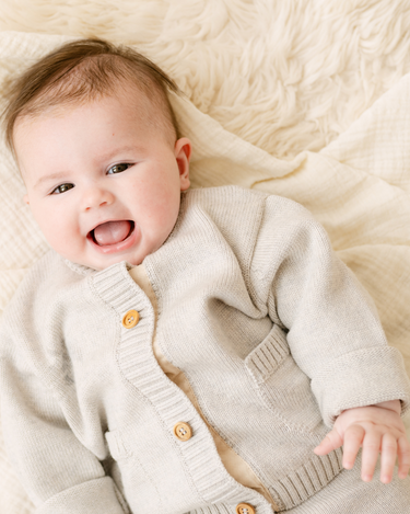 Image shows baby girl wearing merino wool baby cardigan in light heather gray.