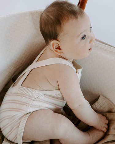 Picture shows baby girl wearing organic cotton knit stripe romper in orchid pink stripes.