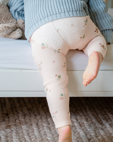 Image shows baby girl wearing organic cotton waffle leggings in bird print.