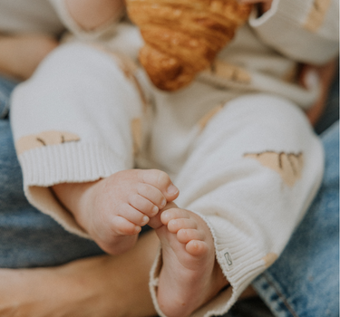 Baby wearing organic cotton knit croissant patterned joggers.
