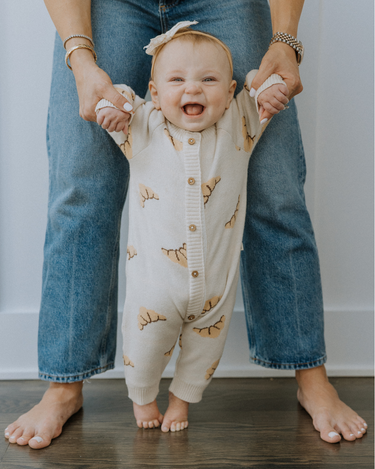 Baby wearing organic cotton knit croissant patterned romper with Magnetic Button closures.