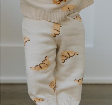 Baby wearing organic cotton knit croissant patterned joggers.