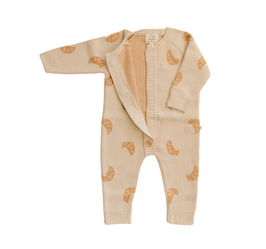 Flat lay photo of organic cotton knit romper with croissant pattern and magnetic buttons from neck to crotch.