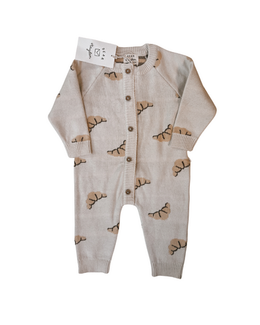 Flat lay image on white background of organic cotton knit croissant patterned romper with Magnetic Button closures.