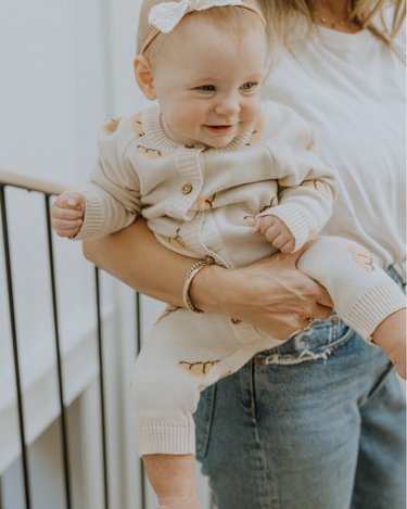 Baby wearing organic cotton knit croissant patterned romper with Magnetic Button closures.