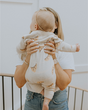 Baby wearing organic cotton knit croissant patterned romper with Magnetic Button closures.
