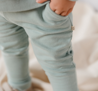 Image shows little boy wearing Organic Cotton Italian fleece joggers in jade color with his hand in one of the pockets.