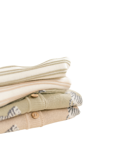Image shows stack of organic cotton knit pieces for baby and toddler