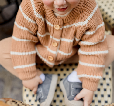 Picture shows little boy wearing organic cotton knit cardigan in acorn and cream stripes with Magnetic Buttons.