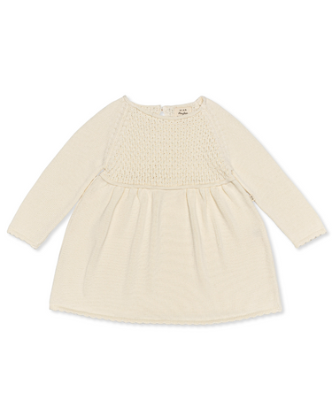 Image Flat lay image of knit dress in oatmilk color with sweet details and button detail at the back of the neck.