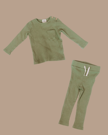Flat lay image of organic cotton rib two piece set in neutral basil color. Set includes a long sleeve top with Magnetic Buttons at the neck in sizes through 12-18 months as well as leggings with a faux drawstring.