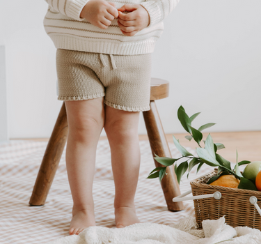 Picture of little girl wearing organic cotton knit shorts in Sandcastle color with faux drawstrings. 