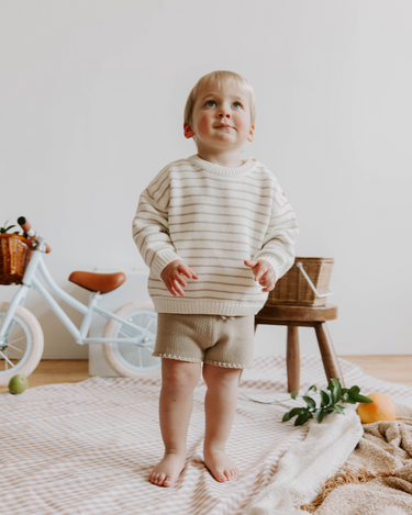 Image of little boy wearing organic cotton knit shorts in sandcastle color with faux drawstrings. 