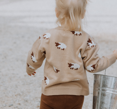 little girl wearing organic cotton beige sweater with sheep jacquard pattern