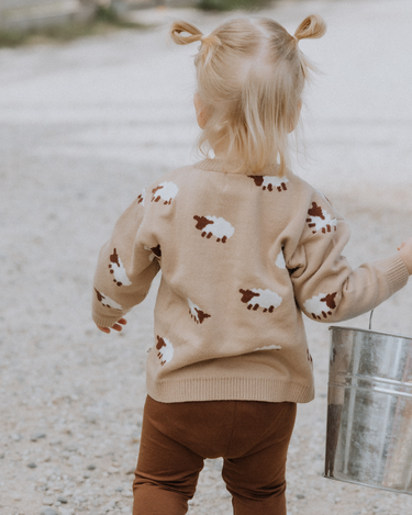 little girl wearing organic cotton beige sweater with sheep jacquard pattern