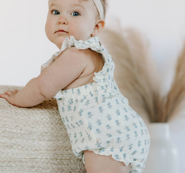 Baby wearing cotton muslin flutter sleeve bubble romper in cheerful floral 