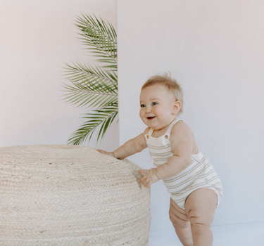Baby wearing organic cotton stripe knit bubble bubble romper in mushroom stripes with magnetic closures at crotch.