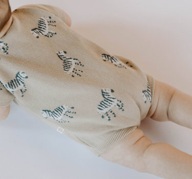 Baby wearing zebra print knit playsuit in mushroom