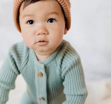 Photo shows baby boy wearing jade organic cotton knit romper with Magnetic Buttons.