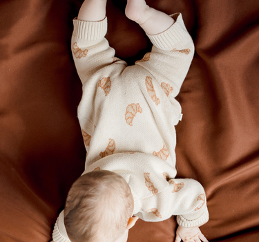 Image shows baby girl wearing organic cotton knit croissant romper.