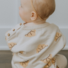 Baby girl wearing organic cotton knit croissant patterned sweater with Magnetic Button closures at the neck. 