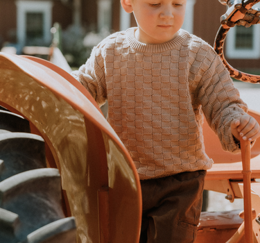 image of little boy wearing Dear Hayden organic cotton basket weave sweater in taupe