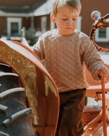 image of little boy wearing Dear Hayden organic cotton basket weave sweater in taupe