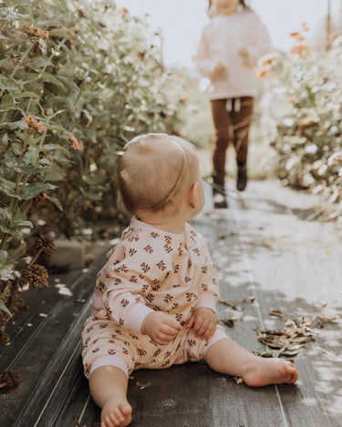 baby girl wearing organic cotton fleece joggers in light pink with rose floral pattern
