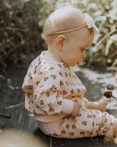 baby girl wearing organic cotton fleece joggers in light pink with rose floral pattern