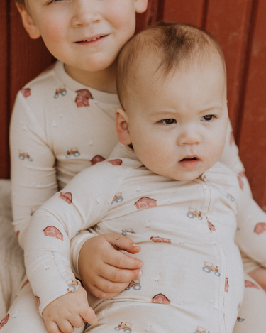 picture of baby boy wearing modal convertible footy pajamas in light beige color with farm print