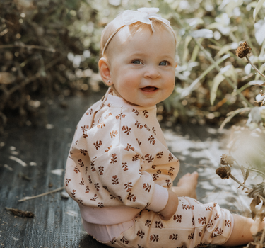 baby girl wearing organic cotton fleece joggers in light pink with rose floral pattern