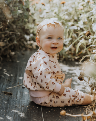 baby girl wearing organic cotton fleece joggers in light pink with rose floral pattern