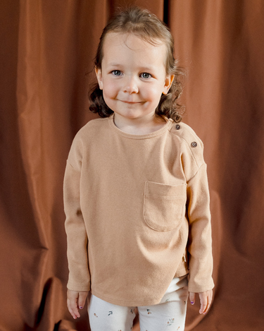 Picture shows toddler girl wearing organic cotton modal rib long sleeve tee in Acorn with Magnetic Buttons at the neck.