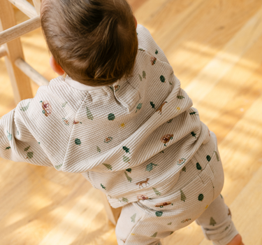 Image shows baby boy wearing organic cotton waffle leggings in camping print.