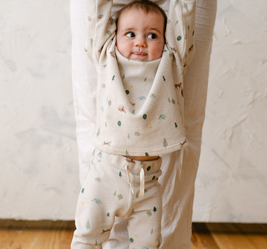 Image shows baby boy wearing organic cotton waffle leggings in camping print.