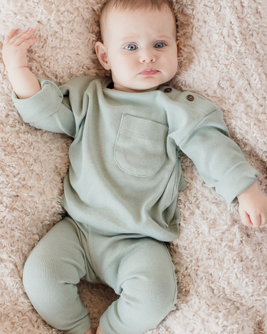 Picture shows baby girl wearing organic cotton modal rib long sleeve tee in jade color with Magnetic Buttons at the neck.